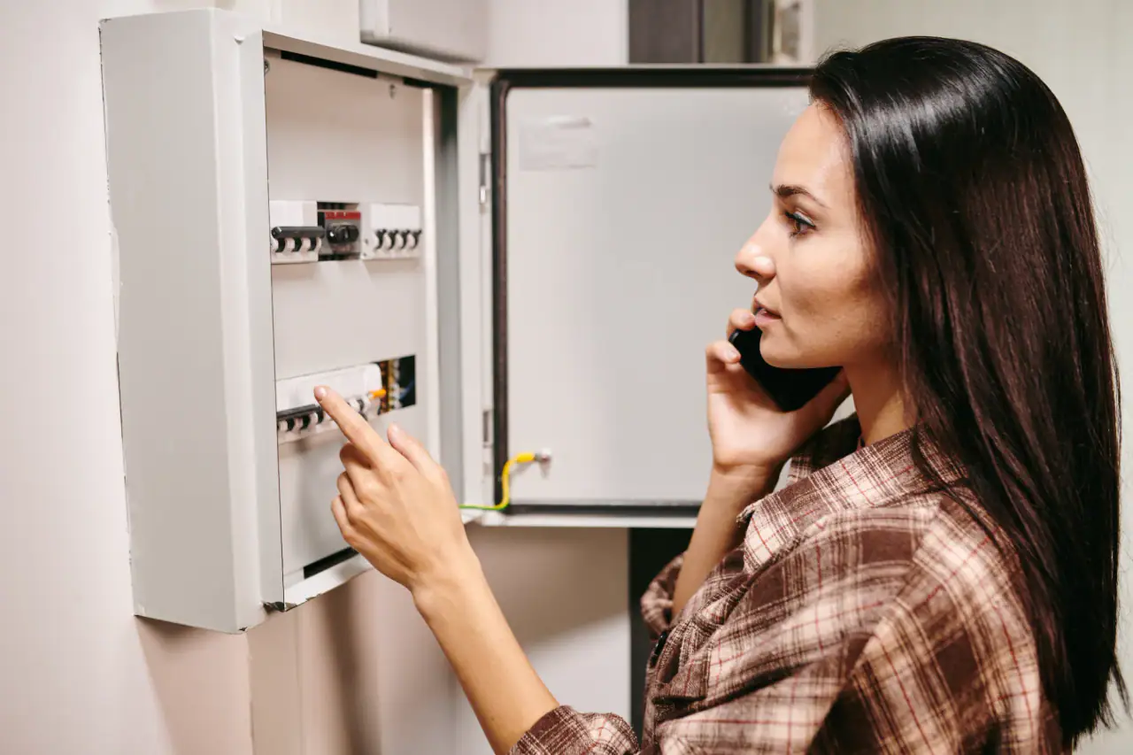 Homeowner on the phone checking the breakers in an electrical panel