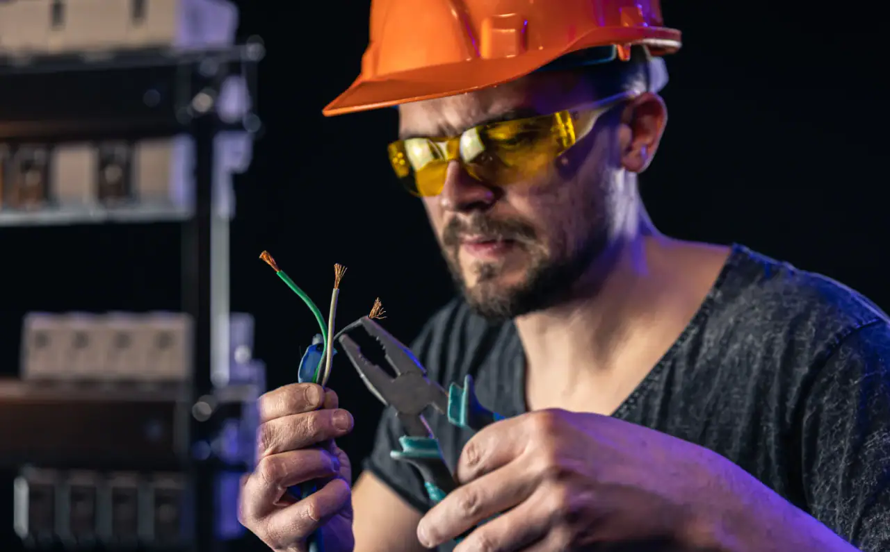 Electrician stripping frayed wires with pliers
